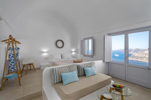 biały pokój z kanapą, łóżkiem i oknem w obiekcie Spectacular view Caldera St V w mieście Megalochori