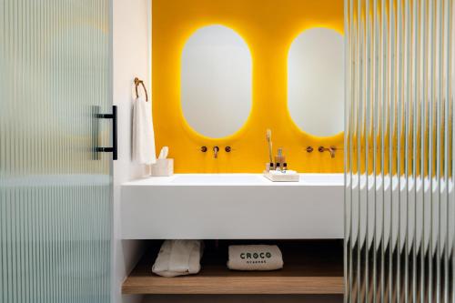 a bathroom with a white sink and two mirrors at Croco Mykonos in Tourlos