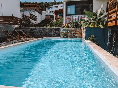 a swimming pool with blue water in front of a house at Logement neuf, Piscine et Climatisation in Saint-Pierre