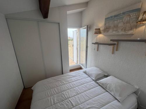 une chambre avec un lit blanc et une fenêtre dans l'établissement SAMARIA VILLAGE Joli appartement 5 personnes piscine à Rochelongue Cap d'Agde, au Cap d'Agde
