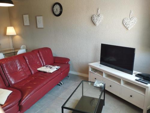 sala de estar con sofá rojo y TV de pantalla plana en Le Bol d'Air, en Cayeux-sur-Mer