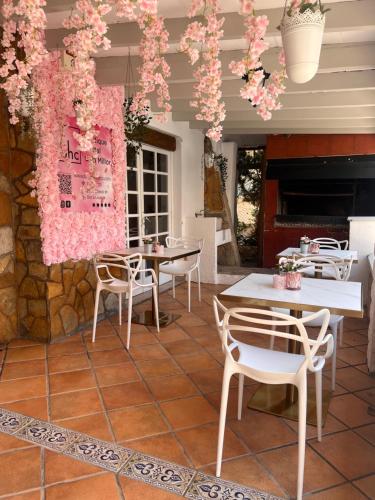 een patio met tafels en stoelen en roze bloemen bij bhc Boutique Hostal Cala Millor in Cala Millor