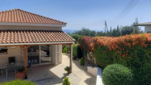 a house with a view of a garden at Villa Best Holiday- breathtaking sea views, amazing garden, private pool, BBQ, next to CORAL BAY, Lower Peyia, Paphos in Peyia