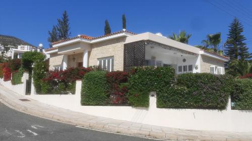 a white house with lots of plants and flowers at Villa Best Holiday- breathtaking sea views, amazing garden, private pool, BBQ, next to CORAL BAY, Lower Peyia, Paphos in Peyia