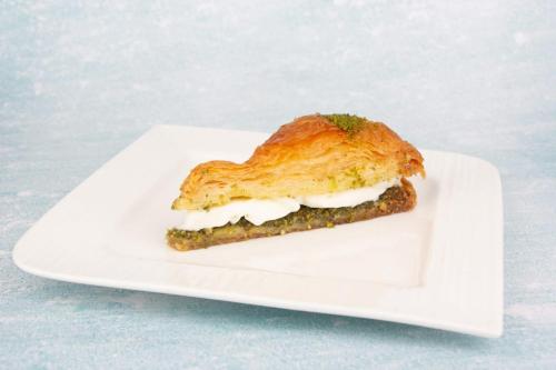 a sandwich on a white plate on a table at ALYA Hotel in Barka