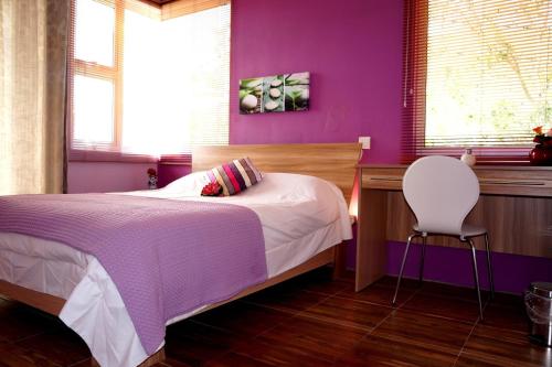 Dormitorio púrpura con cama y silla en Le Morne Kite Villas en La Gaulette
