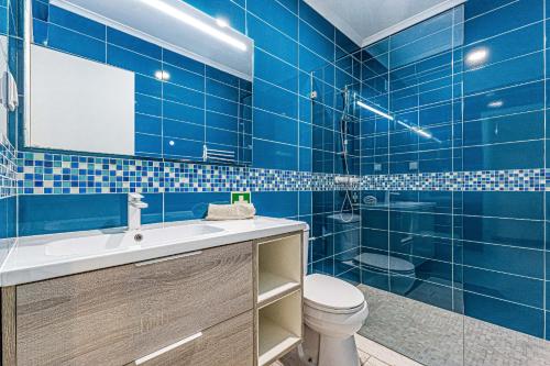 La salle de bains est pourvue de carrelage bleu, de toilettes et d'un lavabo. dans l'établissement By The Sea Algarve Golden Properties, à Armação de Pêra