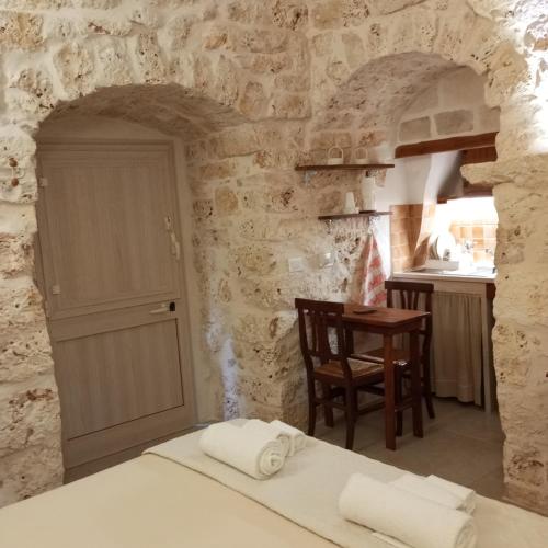 ein Schlafzimmer mit einem Bett und eine Küche mit einem Tisch in der Unterkunft Sotto la pergola in San Michele Salentino