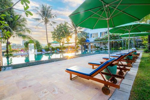 a row of lounge chairs with umbrellas next to a pool at The B Resort in Kampot