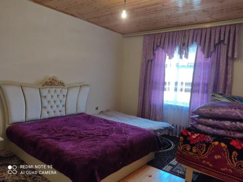 ein Schlafzimmer mit einem Bett mit violetter Bettwäsche und einem Fenster in der Unterkunft Lerik Vista House in Lerik