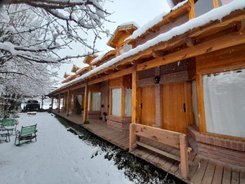 Cabaña de madera con nieve en el porche en Santos Lugares Cabañas en Junín de los Andes