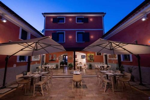 a patio with tables and umbrellas in front of a building at Taverna Ferrigno in Padula