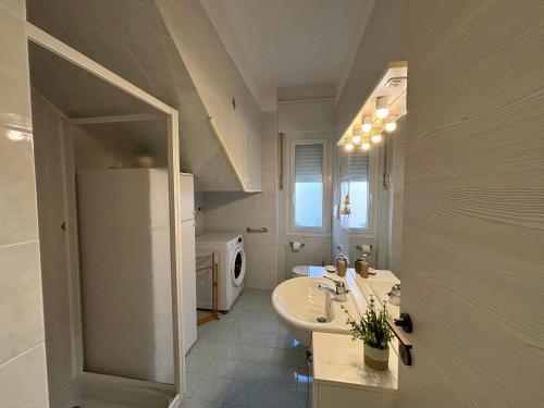 a white bathroom with a sink and a refrigerator at New apartment next to the sea in Bordighera
