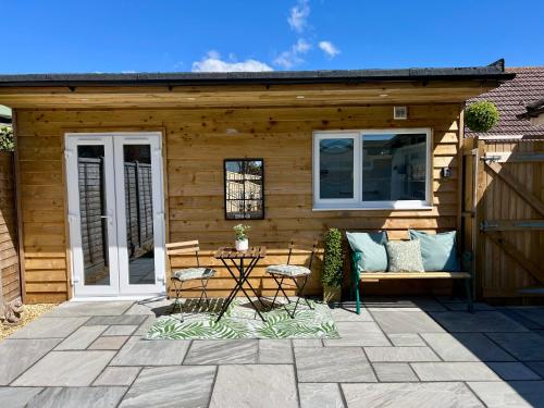 a wooden cabin with a bench and a table at The Mudeford Gem Accommdation in Christchurch