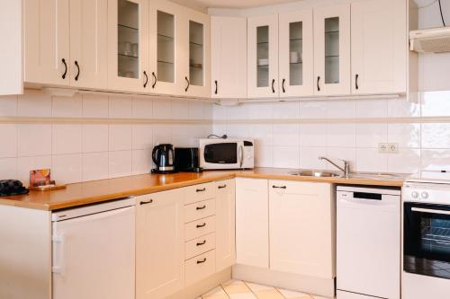 cocina blanca con armarios blancos y microondas en De Steltloper en Zandvoort