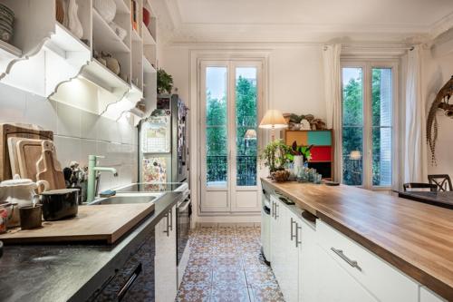 une cuisine avec des armoires blanches et un comptoir en bois dans l'établissement Appart typique Montmartre, à Paris
