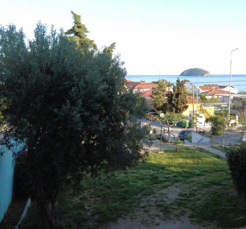 a tree in a yard with the ocean in the background at Dimitras apartment in Paleo Tsifliki