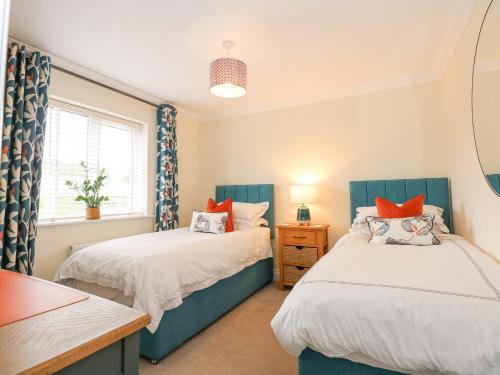 a bedroom with two beds and a table and a window at Coral House in Cromer