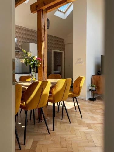 a dining room with a table and yellow chairs at Štupartská - Attic Old Town Residence in Prague