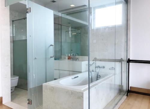 La salle de bains est pourvue d'une baignoire et d'une douche en verre. dans l'établissement A Chic & Comfy 3BR EmbassyView Suite FREE Parking, à Kuala Lumpur