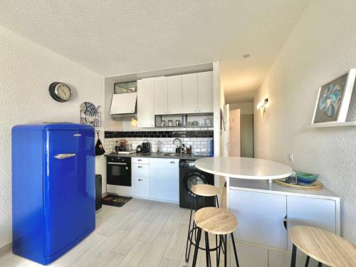 Il comprend une cuisine équipée d'un réfrigérateur bleu et d'une table. dans l'établissement Le Flamant des Marines, 5 min de la plage, au Grau-du-Roi
