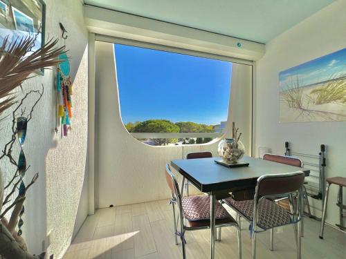 une salle à manger avec une table et des chaises et une fenêtre dans l'établissement Le Flamant des Marines, 5 min de la plage, au Grau-du-Roi