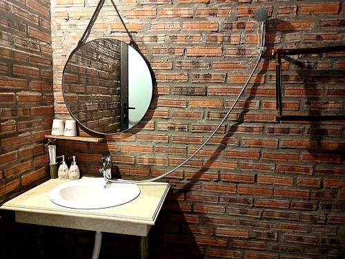 a bathroom with a sink and a mirror on a brick wall at Pu Luong Riverside Lodge in Hương Bá Thước
