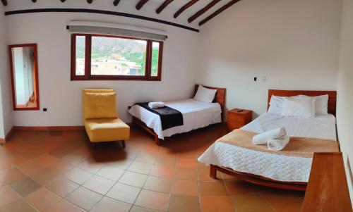 a bedroom with two beds and a chair and a window at Hotel Villasaurio in Sáchica