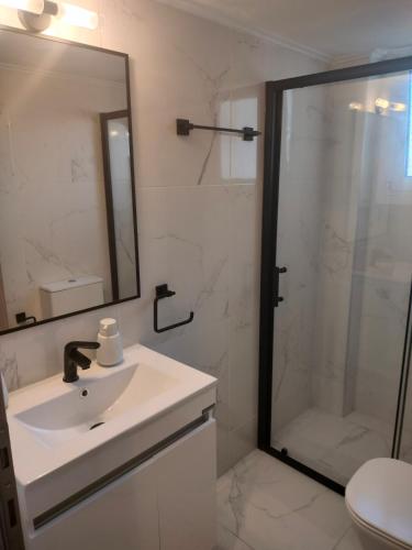 a bathroom with a sink and a shower with a mirror at Luxury sea apartment in Loutraki
