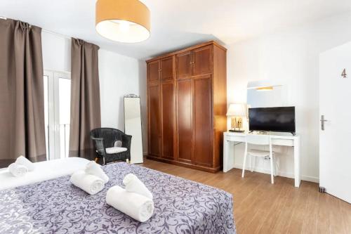 a bedroom with a bed and a desk and a television at BLife Galya private rooms in Faro