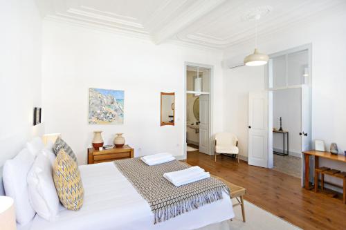 een witte slaapkamer met een bed en een tafel bij Casa Rosa in Vila Real de Santo António