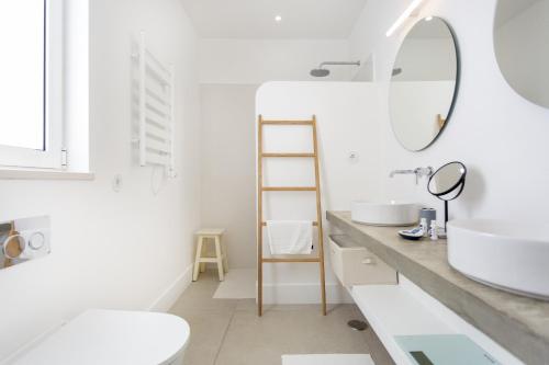 a white bathroom with a sink and a mirror at Casa Rosa in Vila Real de Santo António