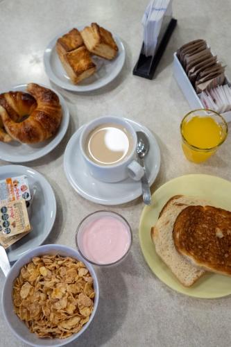 Hotel Belgrano في سان لويس: طاولة مع أطباق من طعام الإفطار وكوب من القهوة