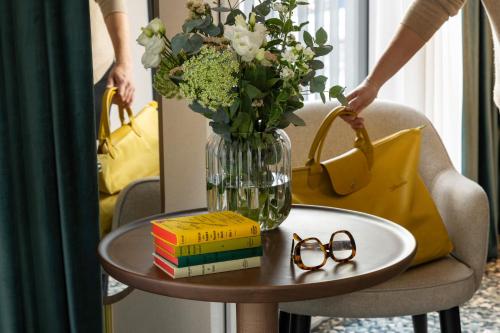 a table with a vase of flowers and glasses on it at Hotel D Bulle - La Gruyère in Bulle
