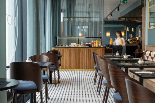 a restaurant with tables and chairs and a chef in the kitchen at Hotel D Bulle - La Gruyère in Bulle