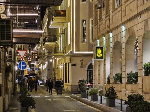 un grupo de personas caminando por una calle por la noche en Hazz Palace Hotel en Bakú