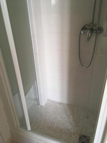 baño con ducha y puerta de cristal en Hôtel de la Mer en Valras-Plage