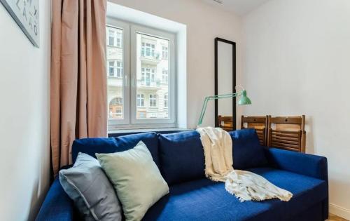a blue couch in a living room with a window at Mikroapartament w centrum in Poznań
