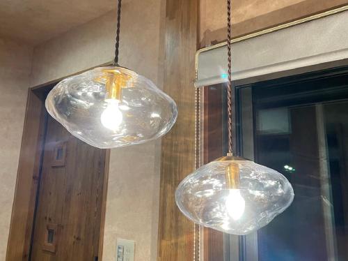two clear glass lights hanging from a wall at Villa 悠生凪 "yunagi" in Kose
