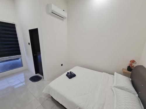 a white bedroom with a bed with a shoe on it at The Bunga and The Daun Housestay 2 in Sungai Besar