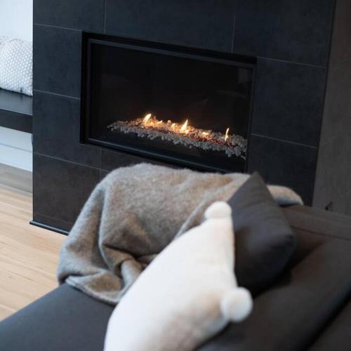 a person laying on a couch in front of a fireplace at Chalet Vintersaga Mont Tremblant in La Conception