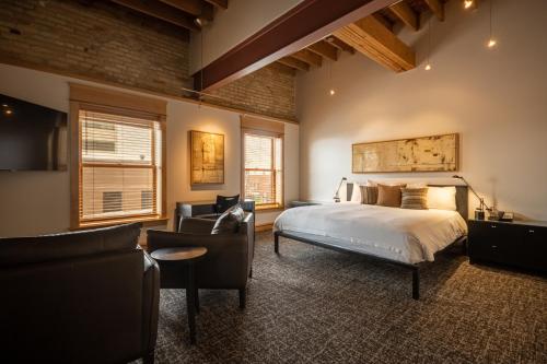 a bedroom with a bed and a couch and chairs at Hotel Donaldson in Fargo