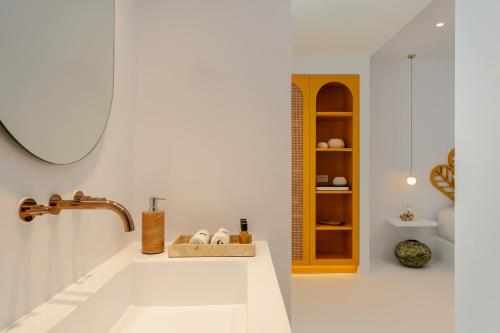 a white bathroom with a sink and a shelf at Croco Mykonos in Tourlos