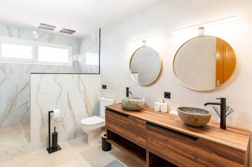ein Badezimmer mit zwei Waschbecken, einem WC und Spiegeln in der Unterkunft Villa Paraíso in Vidreres