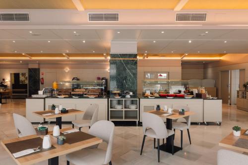 a restaurant with tables and chairs and a kitchen at Sercotel Amistad Murcia in Murcia