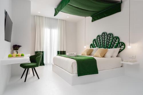 a white bedroom with a bed and a green canopy at Croco Mykonos in Tourlos