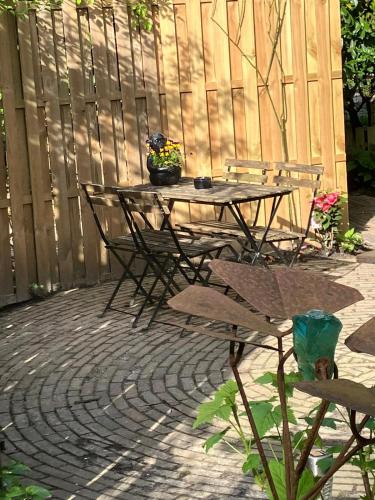 a table and chairs on a patio with a fence at B en B Op Steendam, Tuinkamer onder de appelboom in Steendam