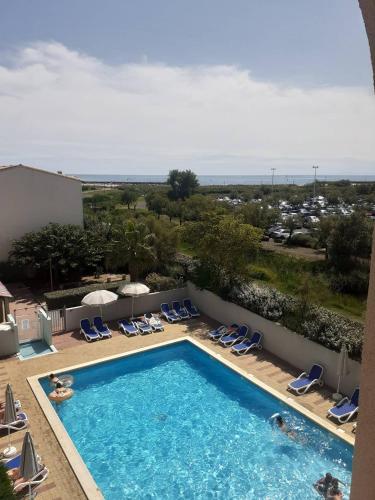 - une piscine avec des chaises et une vue sur le complexe dans l'établissement PRIMAVERA Agréable T2 résidence avec piscine Plage Richelieu Cap d'Agde, au Cap d'Agde