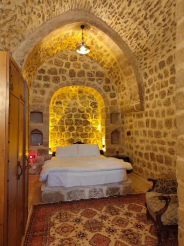 um quarto com uma cama numa parede de pedra em Rumet paşa konağı em Mardin