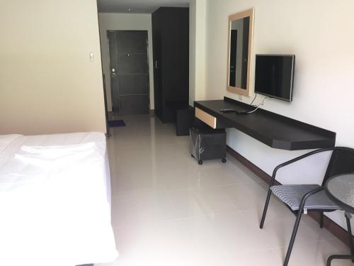 a bedroom with a desk and a bed and a television at B Space Residence in Nong Prue